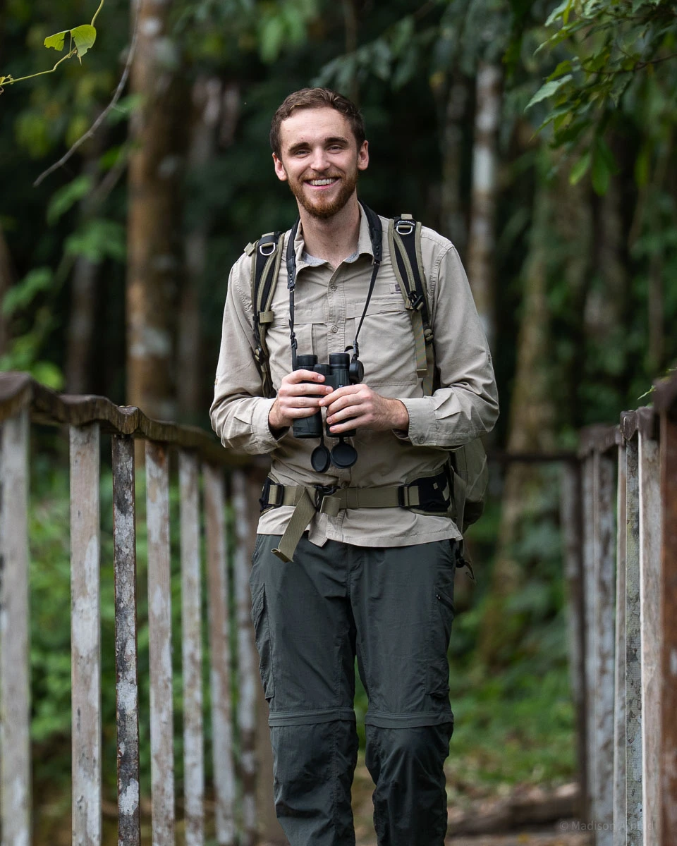 Zach Arnold, TWP's tour biologist, in the field with binoculars