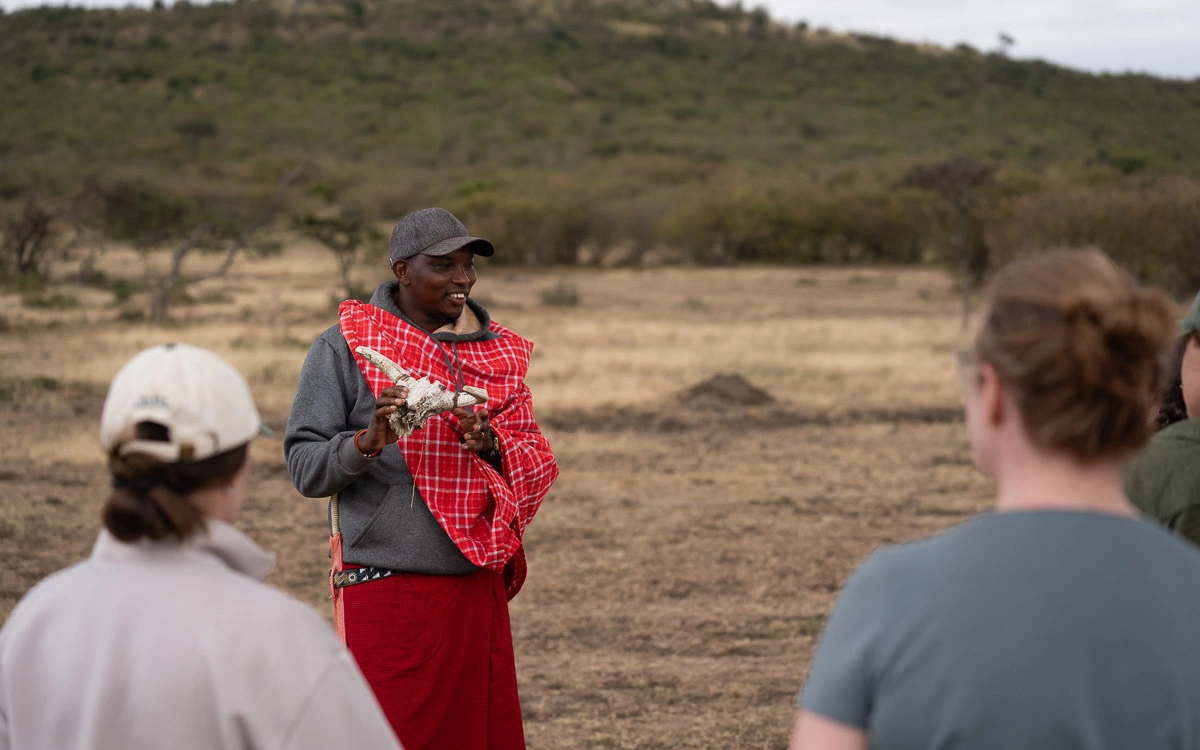 A guide showing guests a skull specimen and explaining the science behind it on the open plains